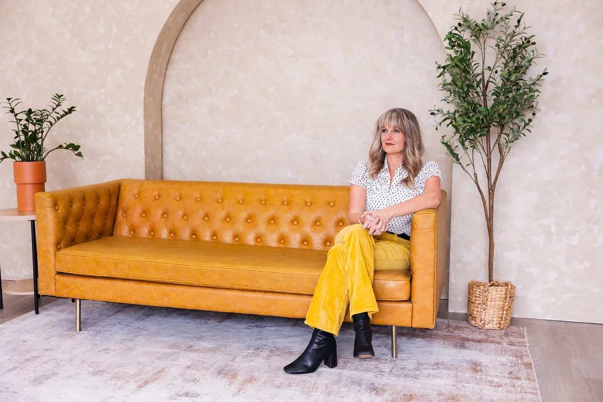 Laura Parker seated on a tufted yellow couch