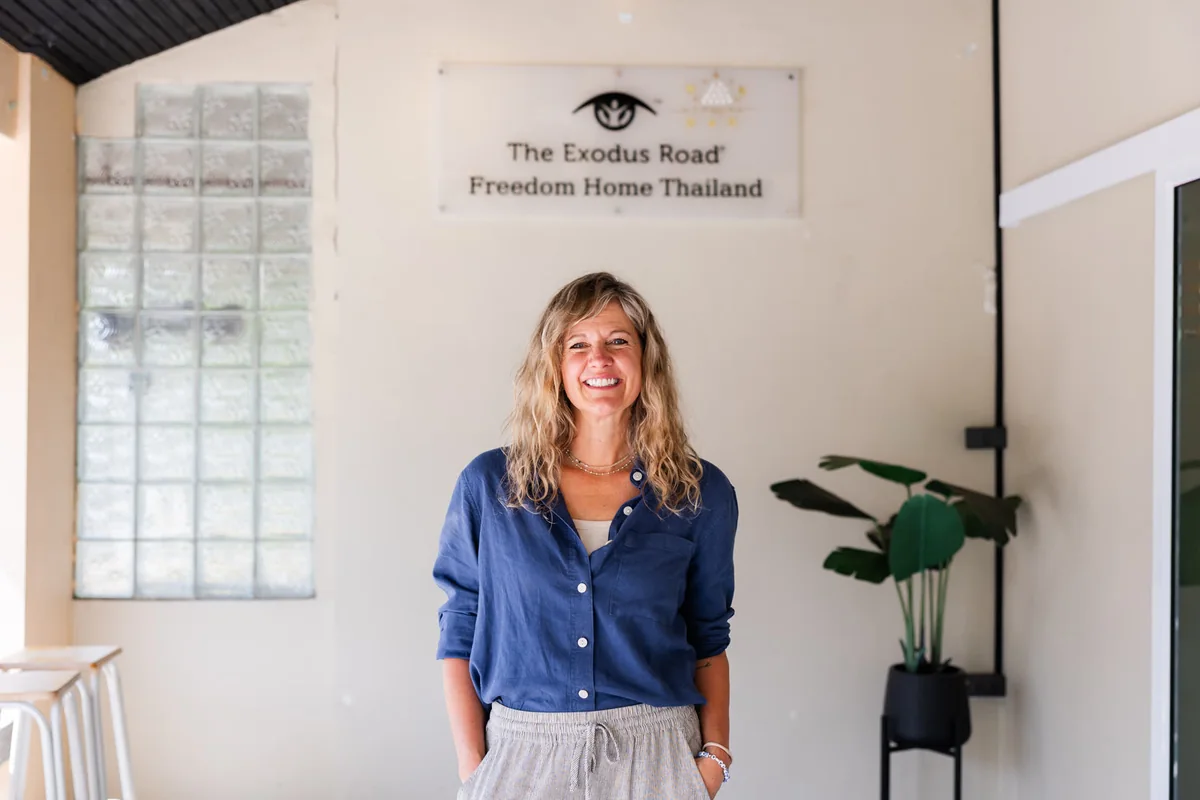 Laura Parker standing beneath The Exodus Road's Freedom Home Thailand sign