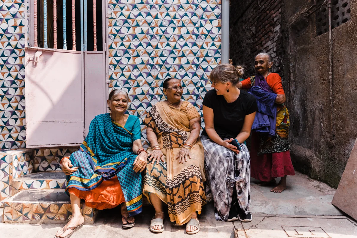 Laura Parker sharing a laugh with two seated women in Mumbai, India